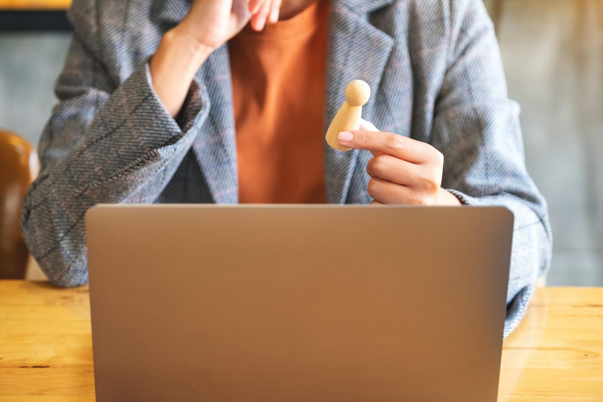 businesswoman-leader-holding-and-choosing-wooden-people-while-working-on-laptop-computer-in-office.jpg